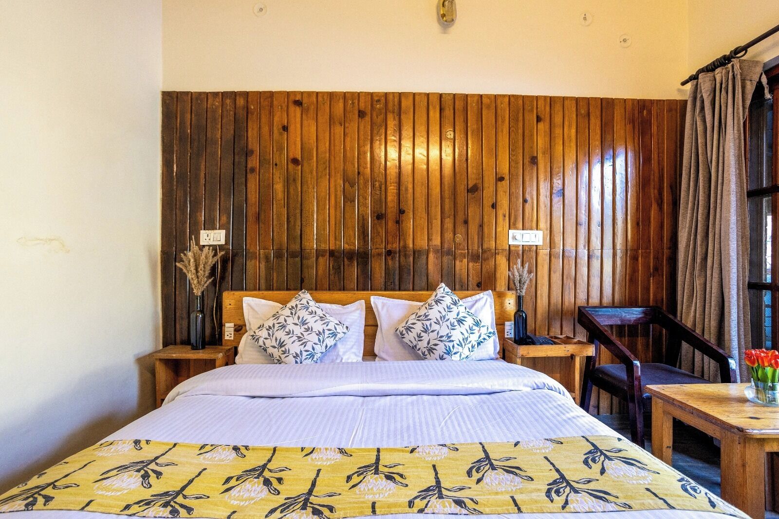 A wooden-paneled bedroom with a bed, two bedside tables, and a chair.