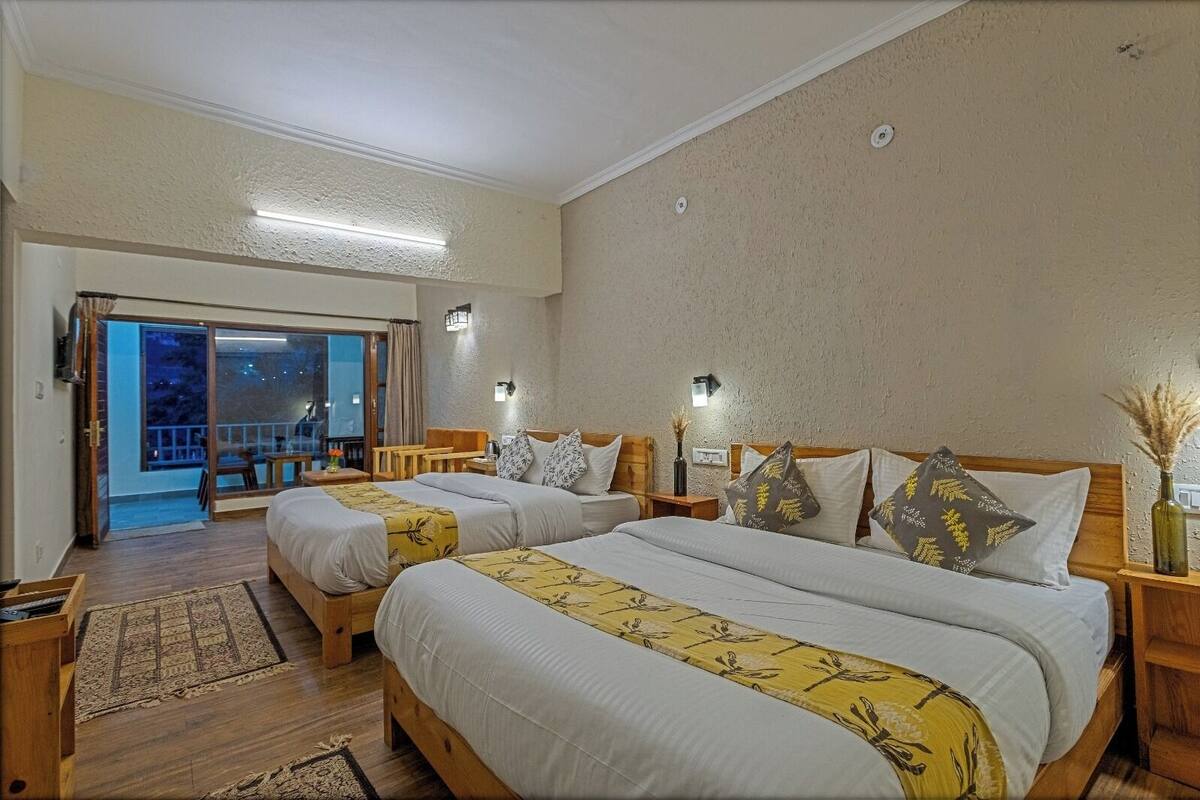 Habitació d'hotel amb dos llits, un balcó i vista al cel nocturn.