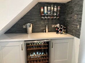 Eine Küche mit Weinkühlschrank, Weinregal und Barbereich mit Flaschen.