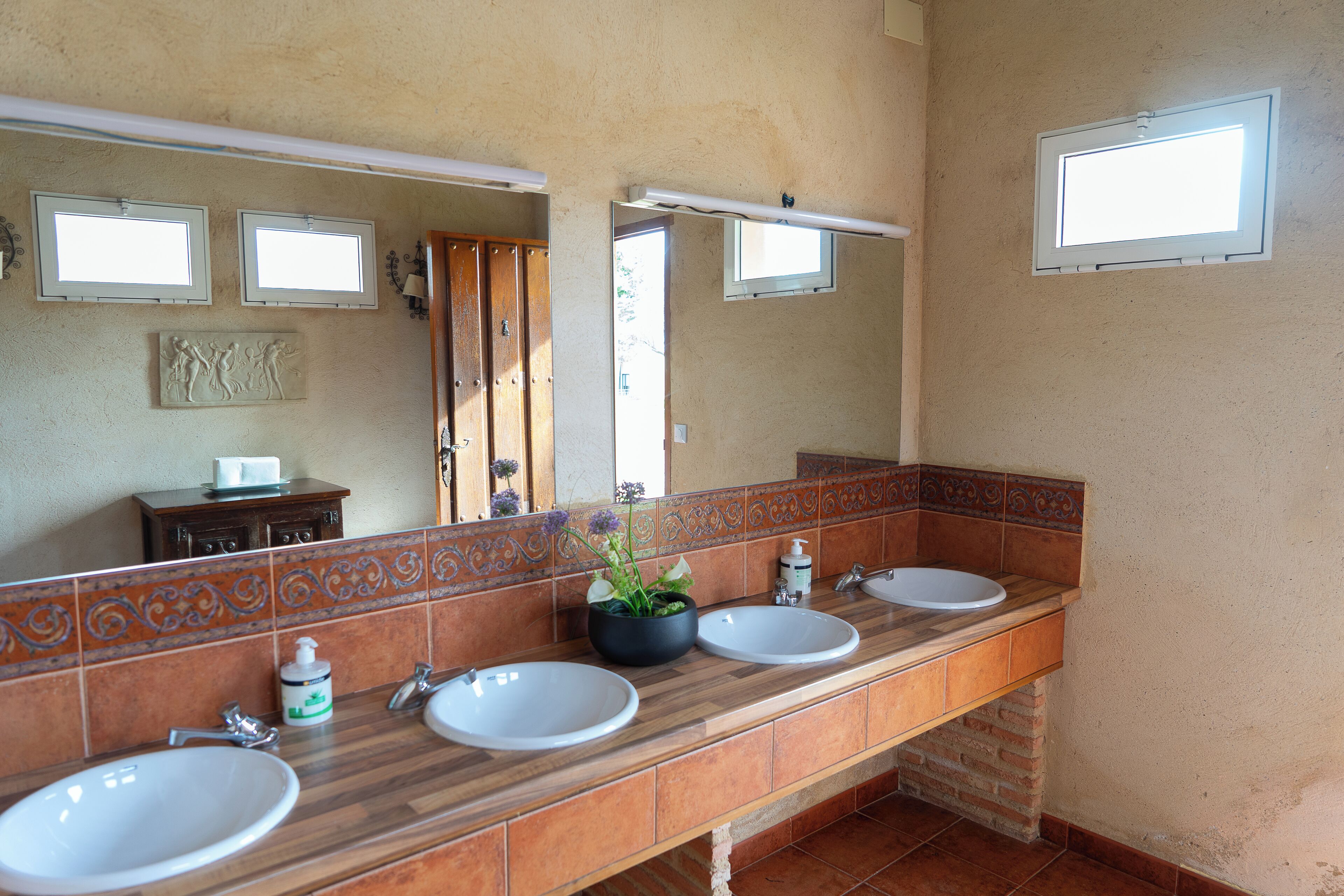 Un baño con dos lavamanos, un espejo y una ventana.