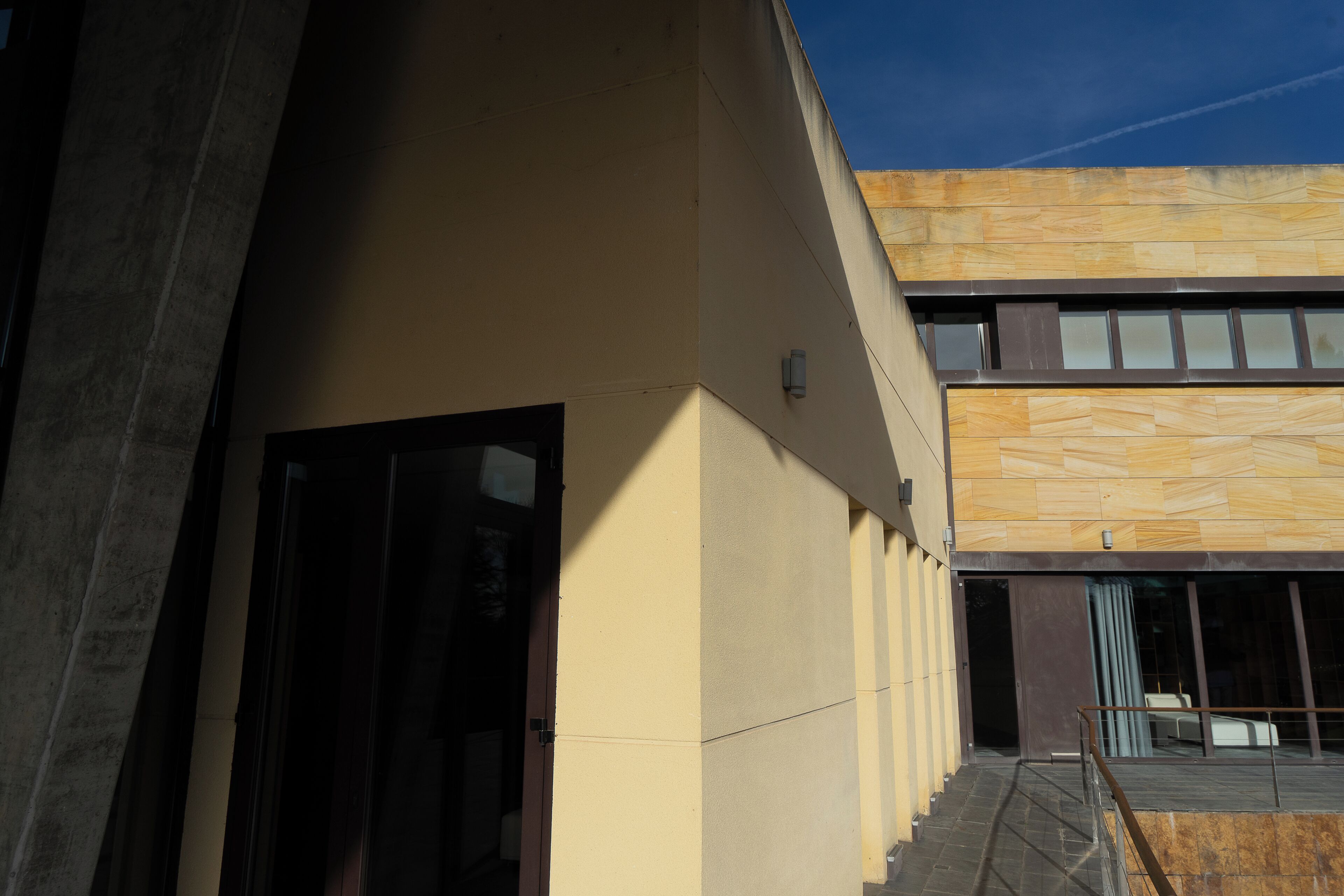 A modern building with a concrete facade and a wooden panel design on the upper section.