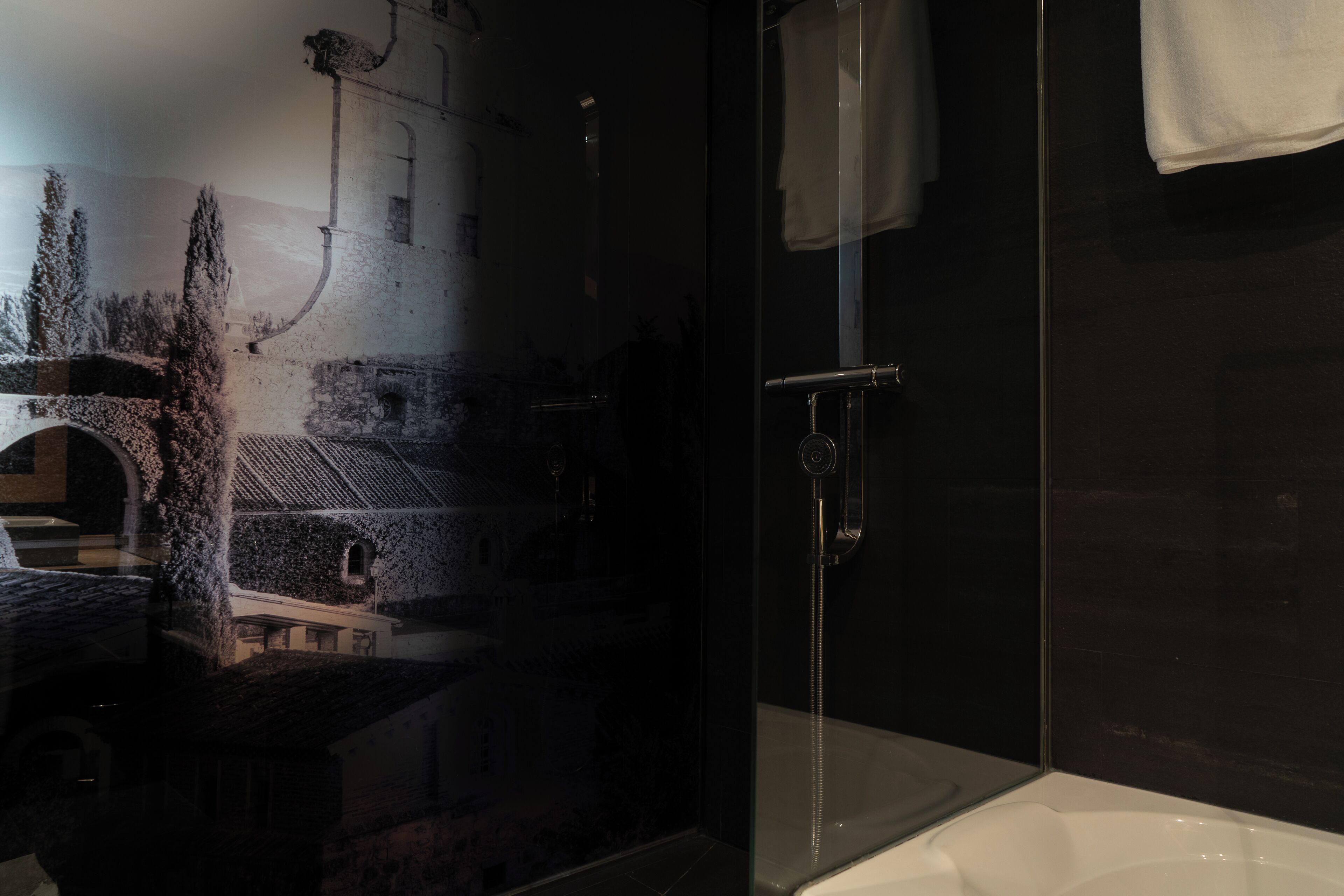 Un baño moderno con cabina de ducha de vidrio, bañera y pared de piedra a la vista.