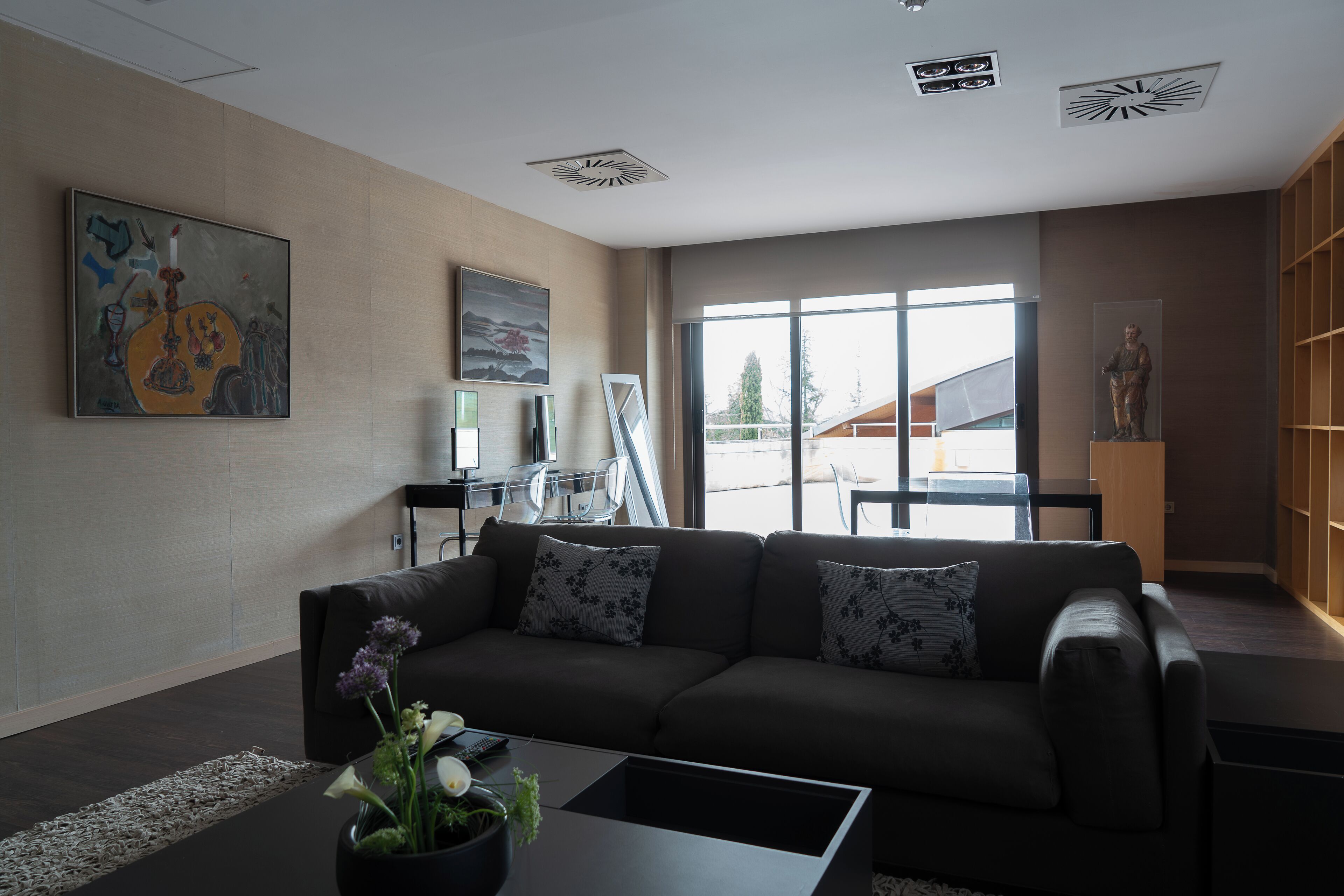 Een moderne woonkamer met een donker leren bank, een salontafel en kunstwerken aan de muur.