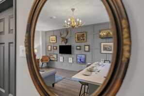 A dining area with a long table set for a meal, a mounted deer head on the wall, and a chandelier above. -  Pools Cottages | Warwickshire Countryside Luxury (Coventry)