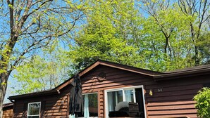 Une cabane dotée d’une véranda, d’un espace salon extérieur et d’un barbecue.