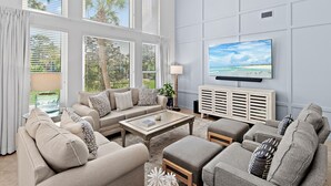 Ein Wohnzimmer mit einer Sofagarnitur, einem Couchtisch und einem Fernseher an der Wand.
