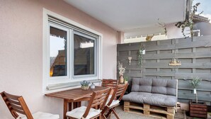 En udendørs patio med et træbord og stole, en grå sofa og et træhegn.