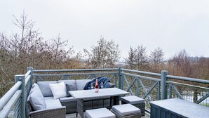 Ein Sitzbereich im Freien mit Tisch, Kissen und einer Flasche.