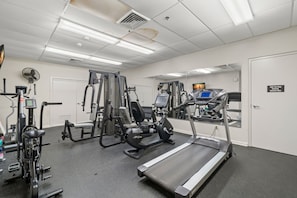 Uma academia com diversos equipamentos de exercício, incluindo esteiras, aparelhos de musculação e uma bicicleta ergométrica.