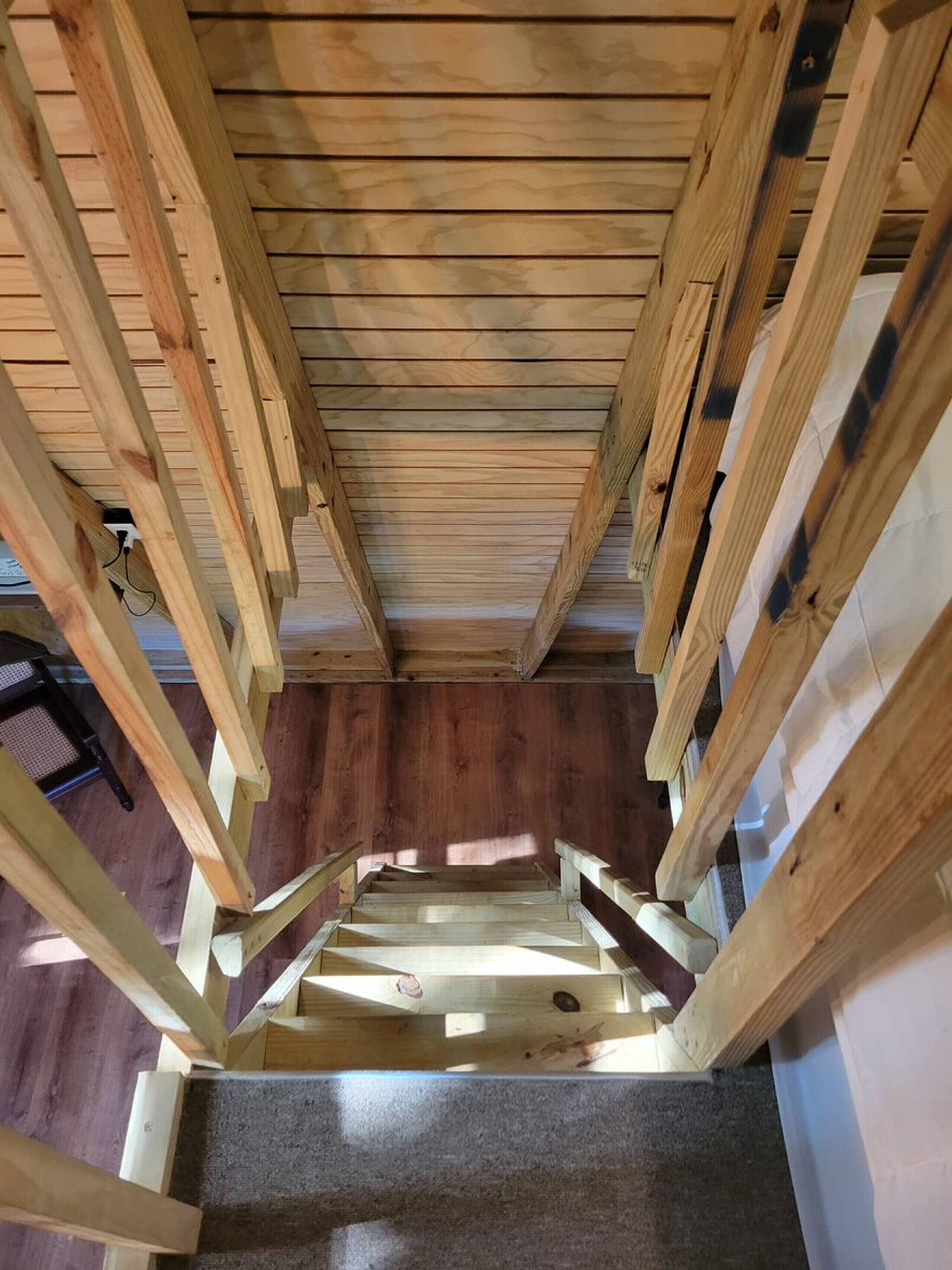 Un escalier en bois avec une petite plateforme recouverte d’une moquette sombre.