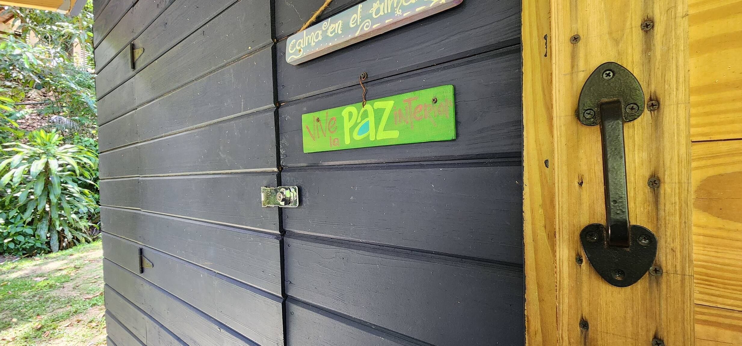 A wooden door with a metal latch and a green sign that reads "Vite le PAZ Interior."