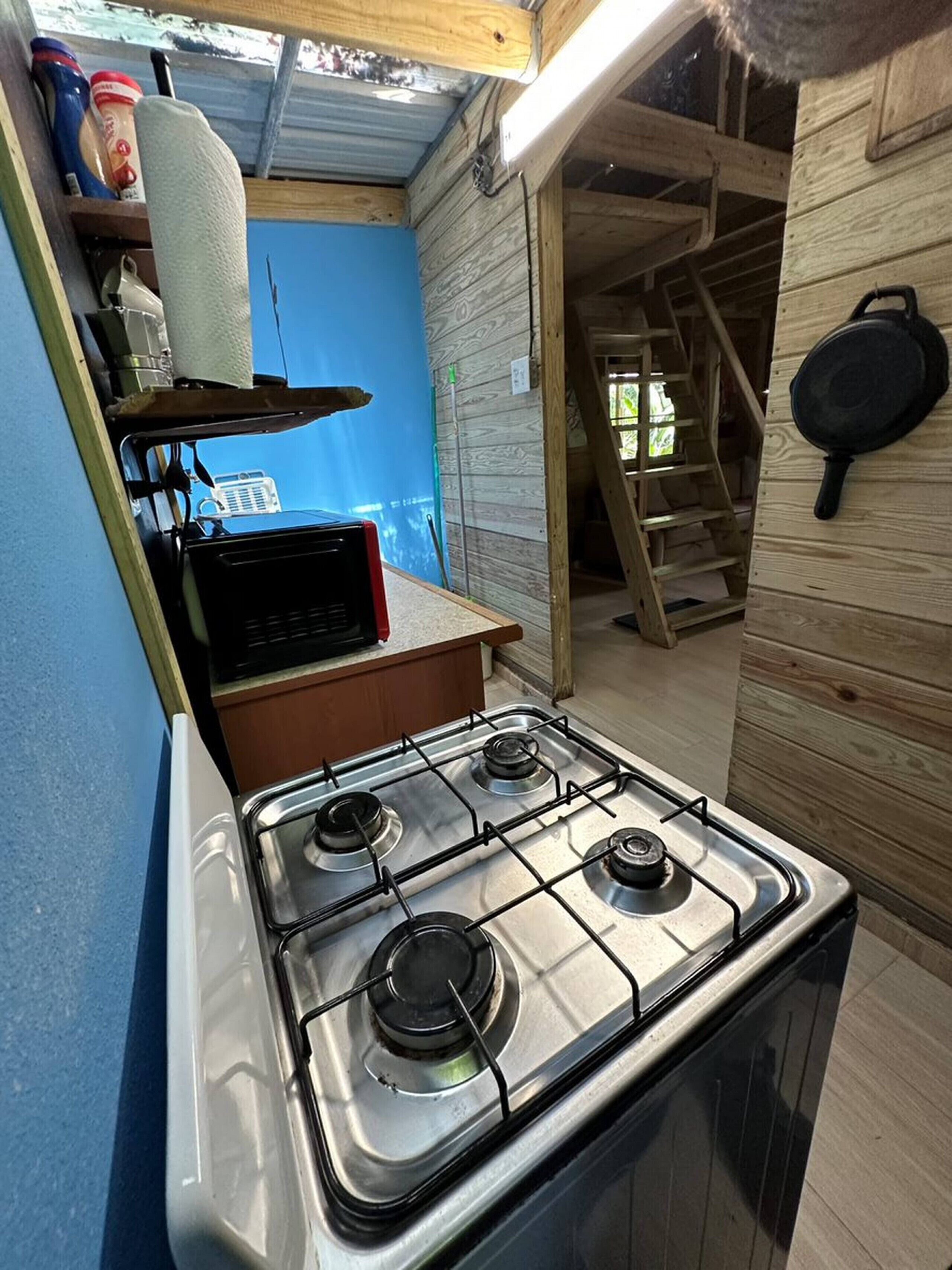 Een kleine keuken met een gasfornuis, houten wanden en een blauwe accentmuur.