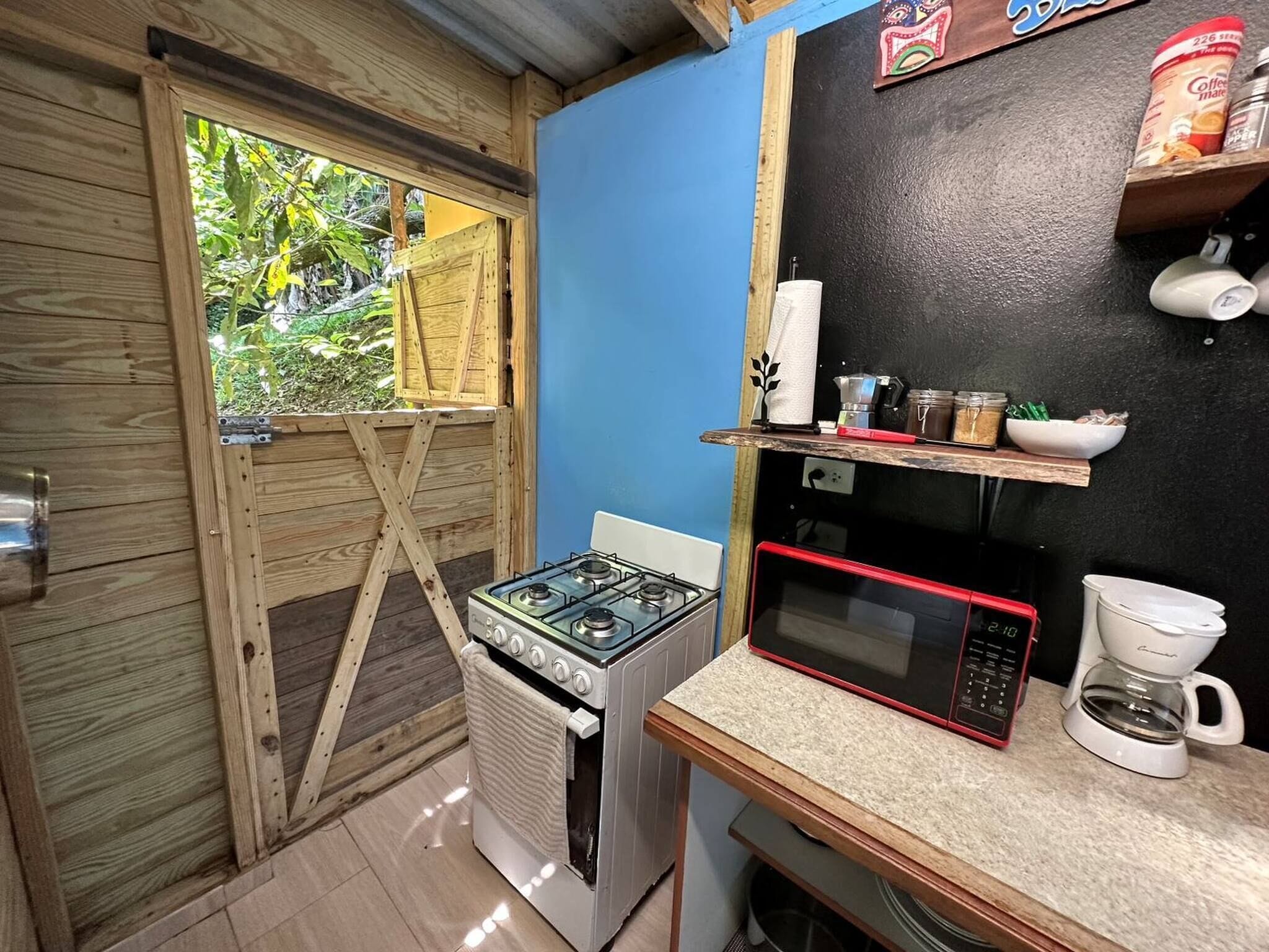 Une cuisine de taille réduite équipée d’une cuisinière à gaz, d’un four à micro-ondes et d’une machine à café.