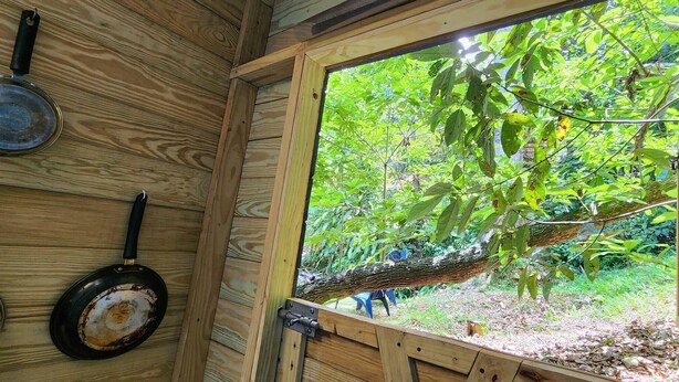 Ein Holzinnenraum mit einem großen Fenster mit Blick auf einen üppigen Garten.
