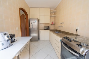 Eine kleine Küche mit Kühlschrank, Herd, Mikrowelle und Toaster.