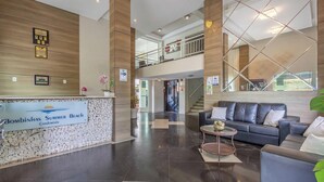 A modern lobby with a reception desk, a lounge area with a sofa and a coffee table, and a staircase leading to an upper level. - Apts in Condo w/ Pool and Gym 450m From the Beach - SBH (Bombinhas)