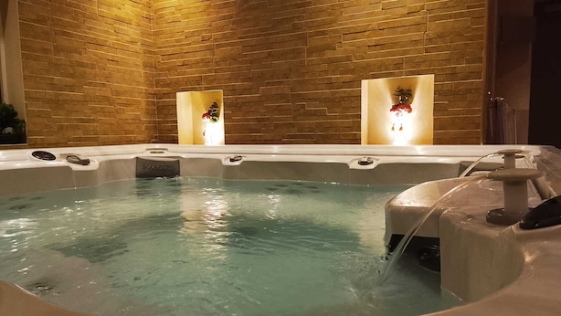 Een bubbelbad met een bakstenen muur op de achtergrond en twee verlichte wandlampen.