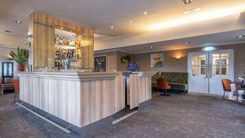 A modern bar area with a wooden counter, a variety of bottles, and a digital screen.