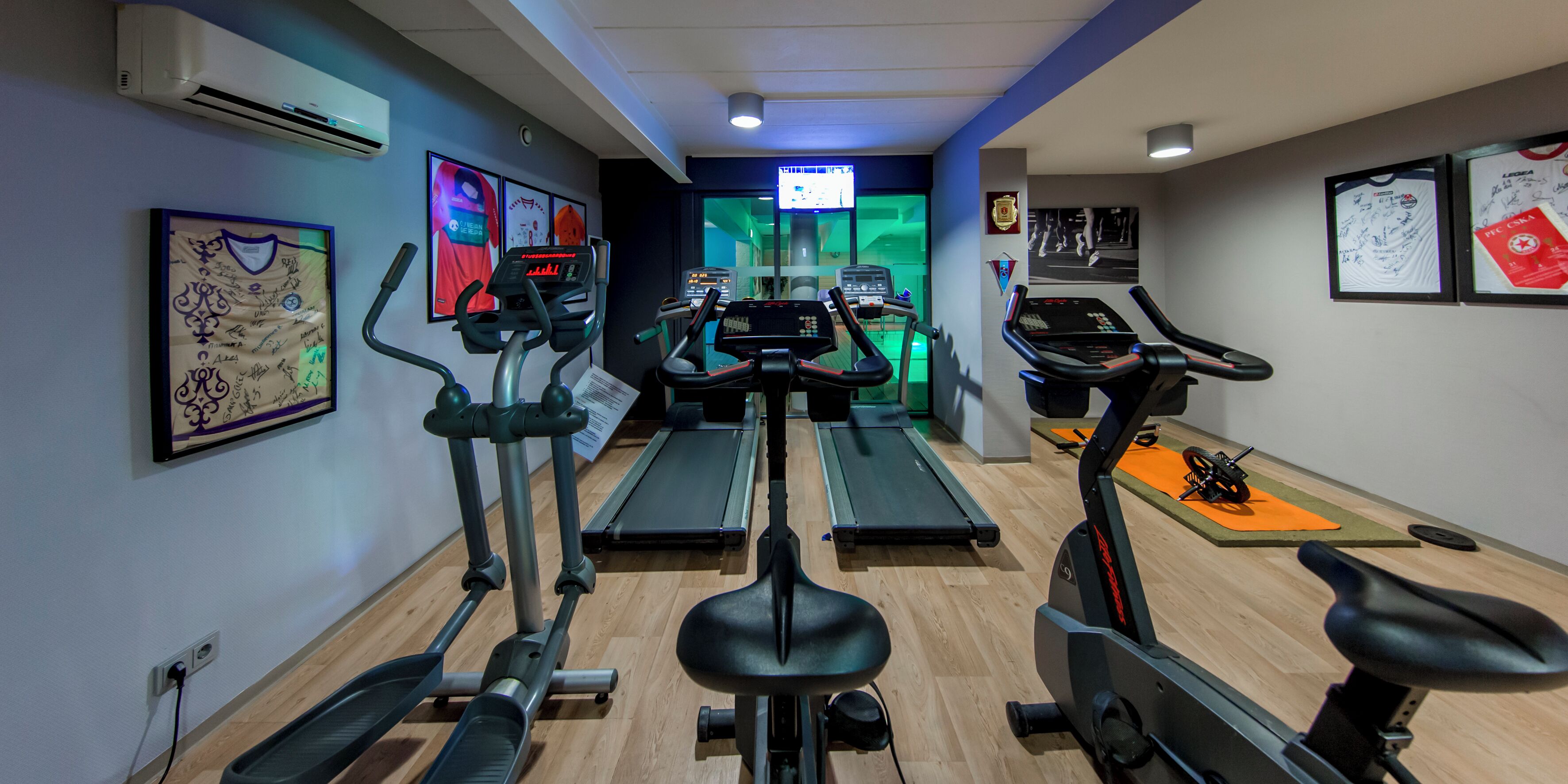 Een fitnessruimte met loopbanden, elliptische trainers en hometrainers.