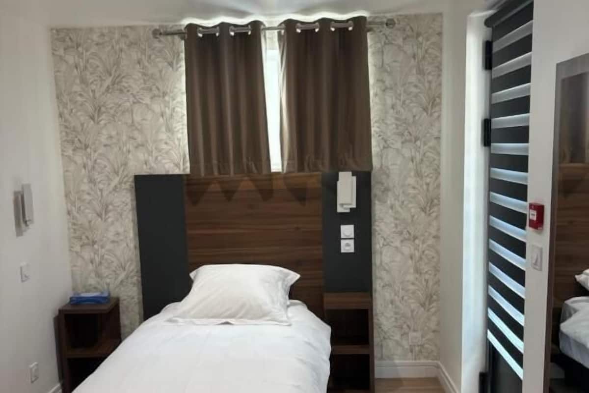 A bedroom with a bed, a nightstand, a wardrobe, and a mirror.