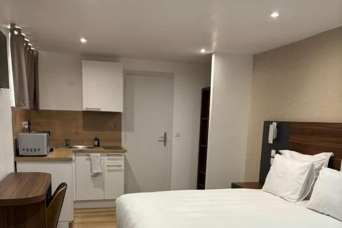 A hotel room with two beds, a kitchenette, and a wooden floor.
