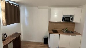 A compact kitchen with white cabinets, a microwave, and a small sink. - Pavillon 92 (La Garenne-Colombes)