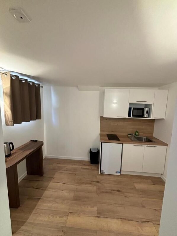 A compact kitchen with white cabinets, a microwave, and a small sink.