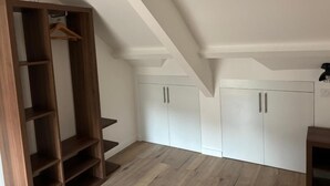 A room with a wooden wardrobe, white cabinets, and a herringbone-patterned floor. - Pavillon 92 (La Garenne-Colombes)