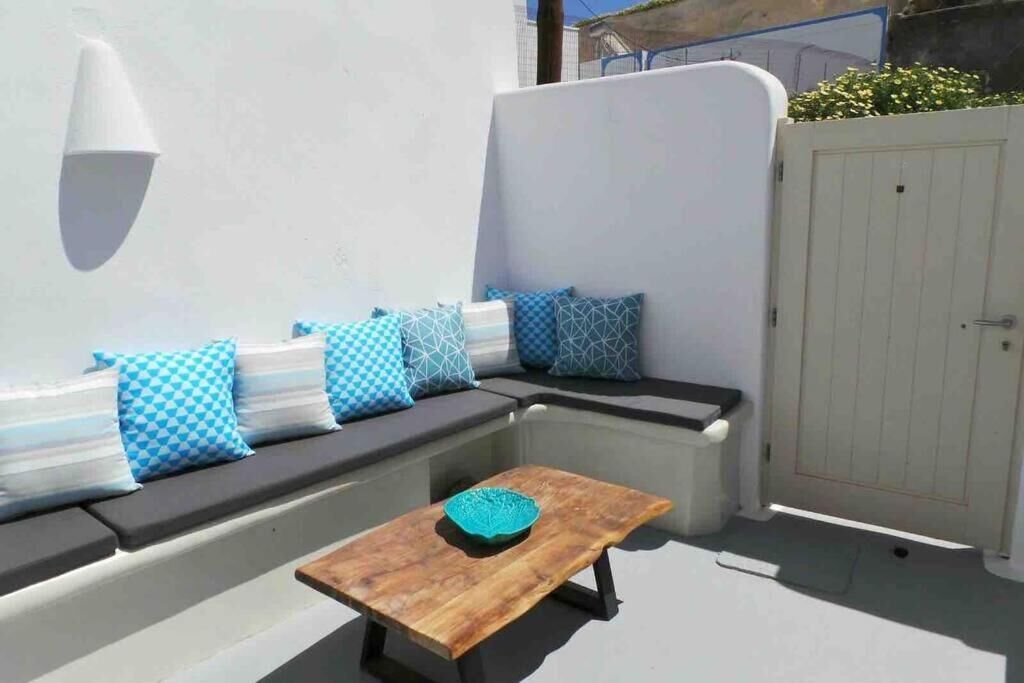Un espace extérieur ensoleillé, aménagé avec une table en bois et des coussins à motifs bleus.