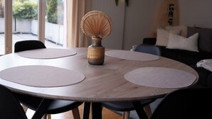 A round wooden table with three circular placemats, a decorative vase, and a surfboard leaning against the wall. - Line UP - 2,5 Zi Whg mit Seeanstoss - Beckenried (Beckenried)