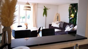 A modern living room with a sofa, dining table, chairs, and a decorative plant. - Line UP - 2,5 Zi Whg mit Seeanstoss - Beckenried (Beckenried)