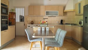 Eine moderne Küche mit Holzausstattung, einer zentralen Kochinsel mit Sitzgelegenheiten, einem Einbauofen und einer Mikrowelle.