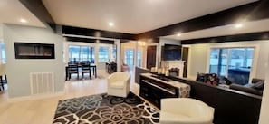 A modern living room with a fireplace, seating area, and large windows.