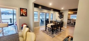 Un salón amplio con un ventanal grande, una zona de comedor con mesa y sillas, y una cocina al fondo.