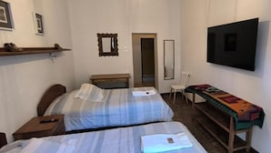 A room with two beds, a TV, a chair, and a small table. - Flying Dog Hostel Cusco (Cusco)