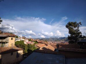 A town with terracotta-roofed buildings, a clear sky, and distant mountains. - Flying Dog Hostel Cusco (Cusco)