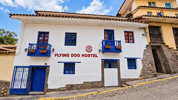 Un edificio con un letrero que dice 'FLYING DOG HOSTEL' y un logotipo que muestra un perro y un avión.