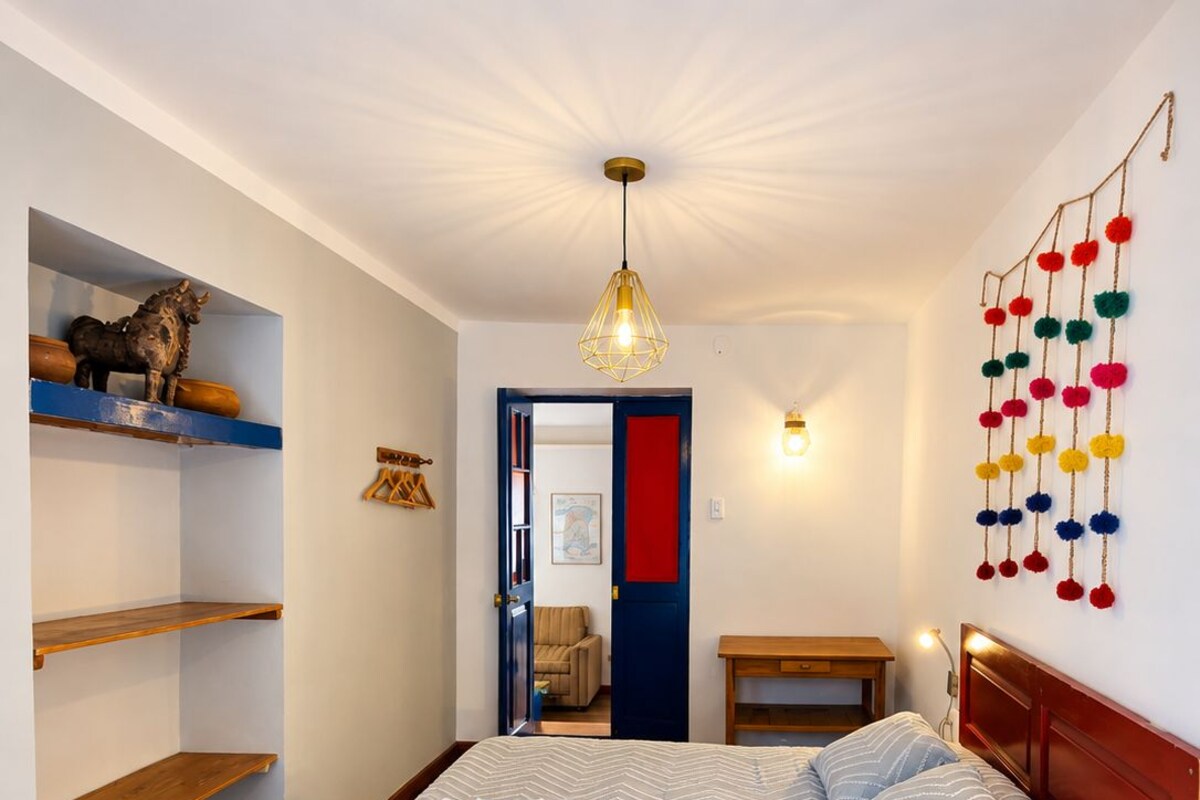 Quarto com cama, prateleiras de madeira, luminária pendente e um objeto decorativo na parede.