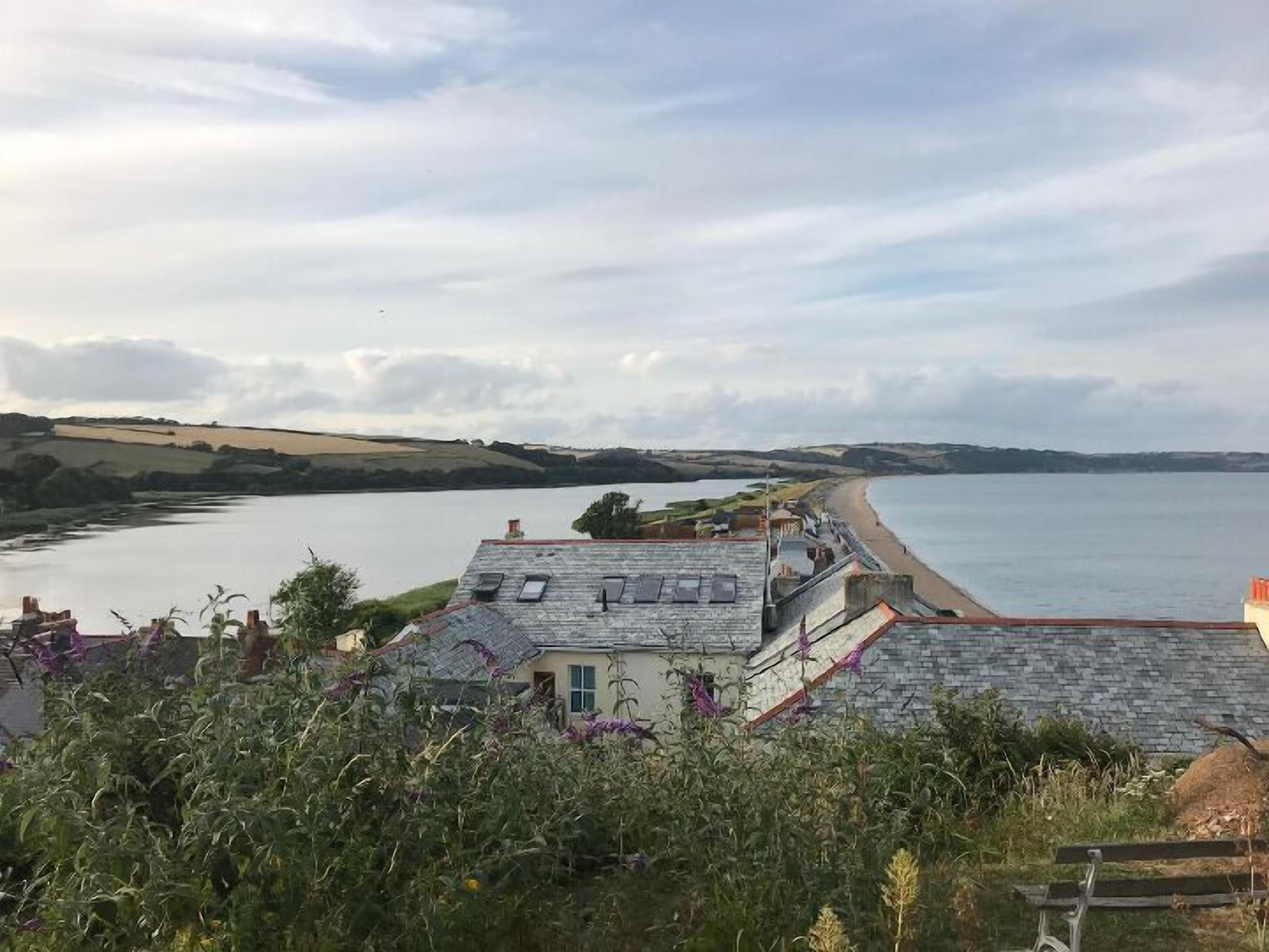 Vista costeira com uma casa dando para uma praia e um corpo de água.
