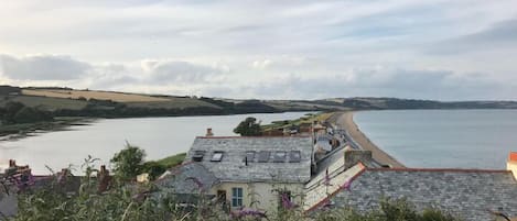 A coastal view with a house overlooking a beach and a body of water.