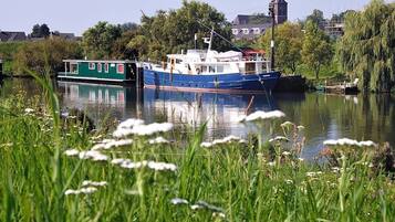 A river with boats, greenery, and a church in the background.