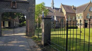 A brick building with a gate, a church with a steeple, and a well-maintained lawn.