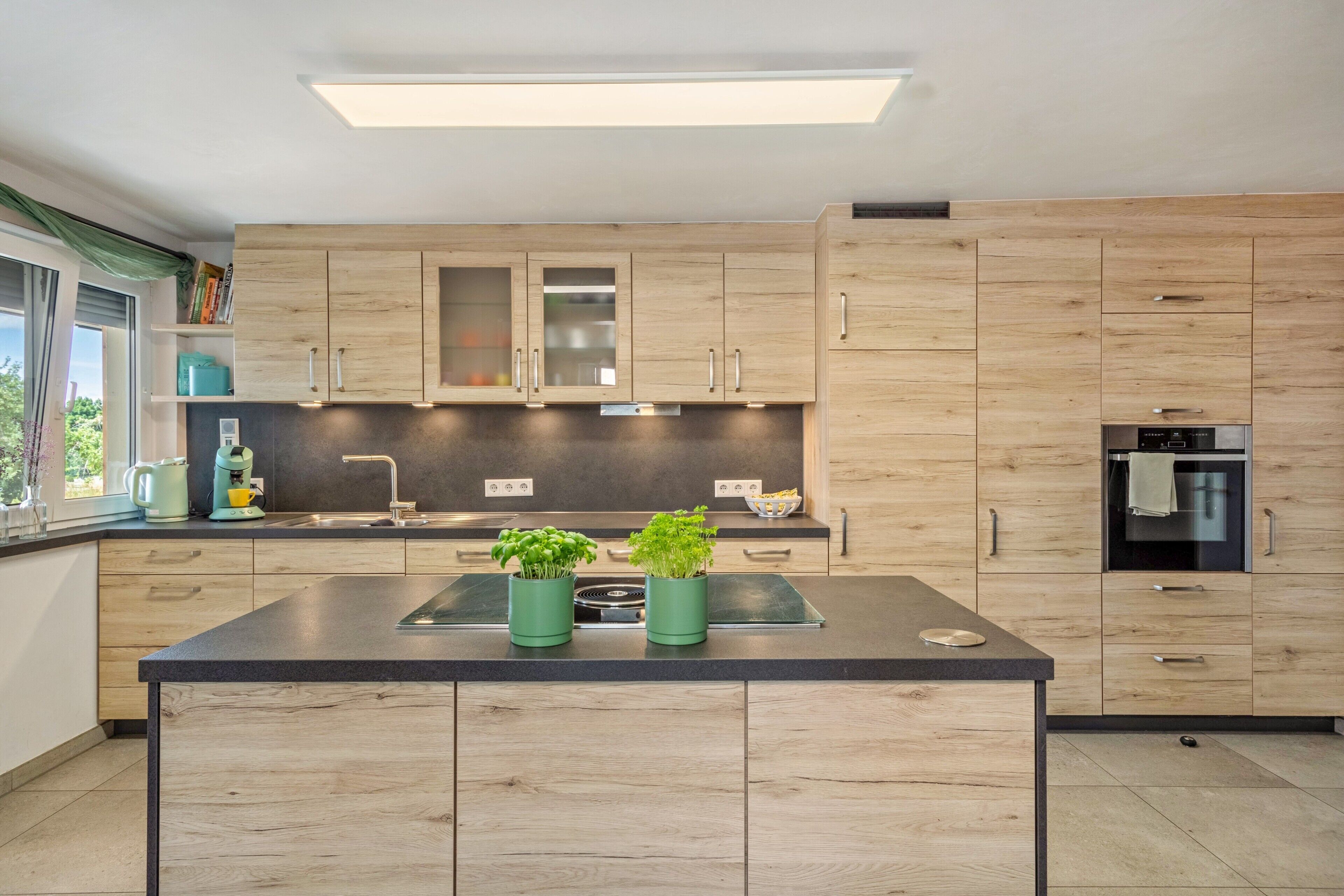 Una cocina moderna con armarios de madera, una isla central y un horno empotrado.