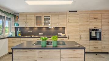 Una cocina moderna con armarios de madera, una isla central y un horno empotrado.