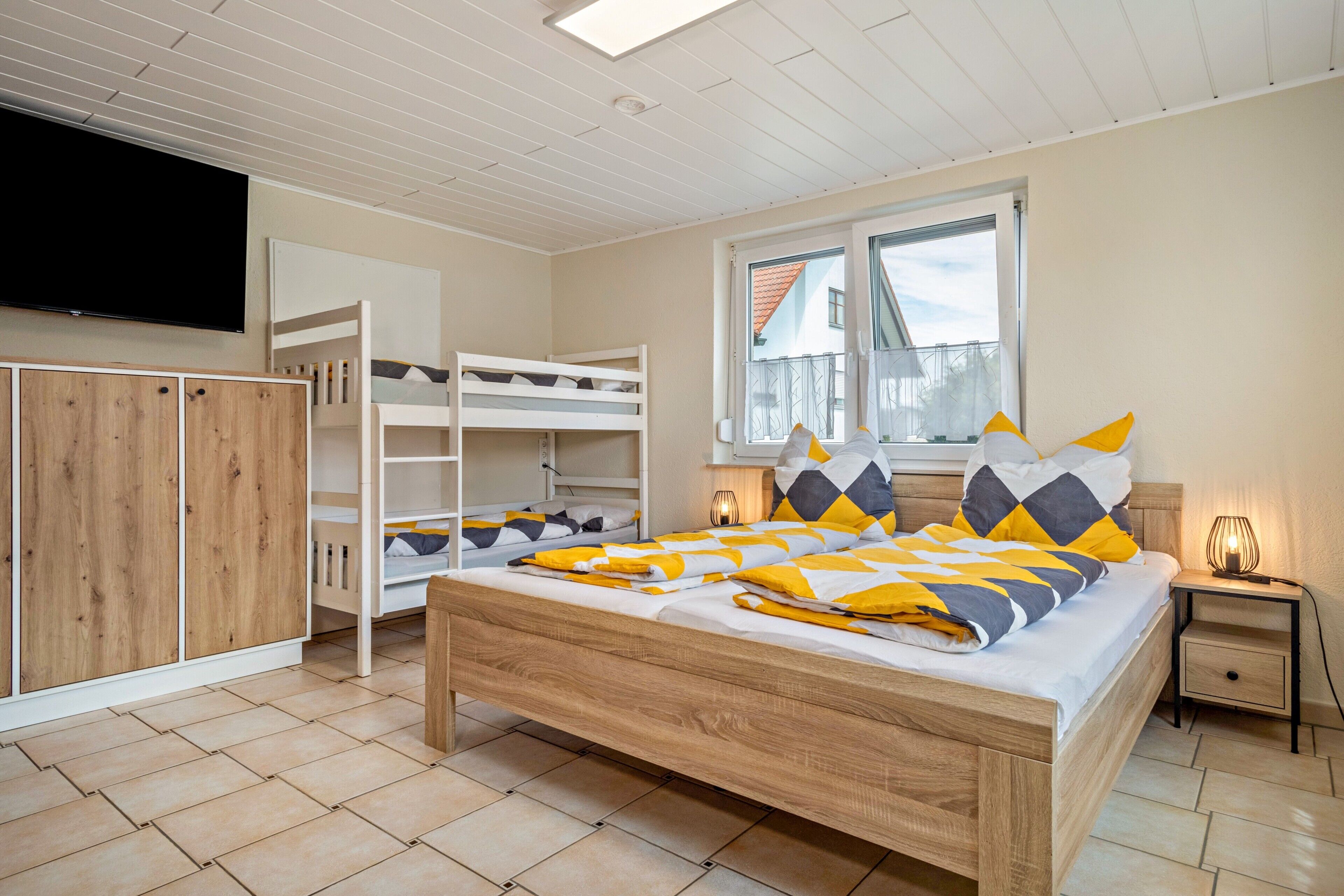 Ein Schlafzimmer mit einem Etagenbett, einem Holzschrank, einem Nachttisch mit Lampe und einem Fenster mit Blick.
