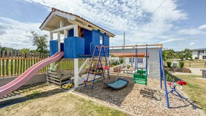 Un parque infantil con tobogán, columpios y una estructura para escalar.