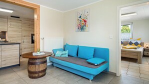 Un espacio habitable moderno con sofá, mesa de madera, zona de cocina y cama.