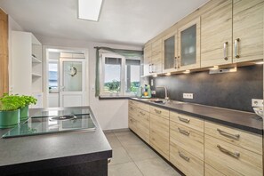 Eine Küche mit Holzausstattung, einer schwarzen Arbeitsplatte, einem eingebauten Herd und einem Fenster mit Blick.
