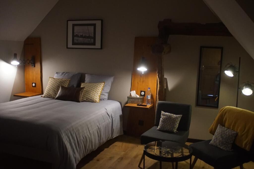 A cozy bedroom with a bed, bedside tables, a chair, and a small table.