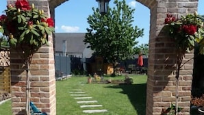 Un arc en pierre mène à un espace verdoyant où se trouve un sentier.